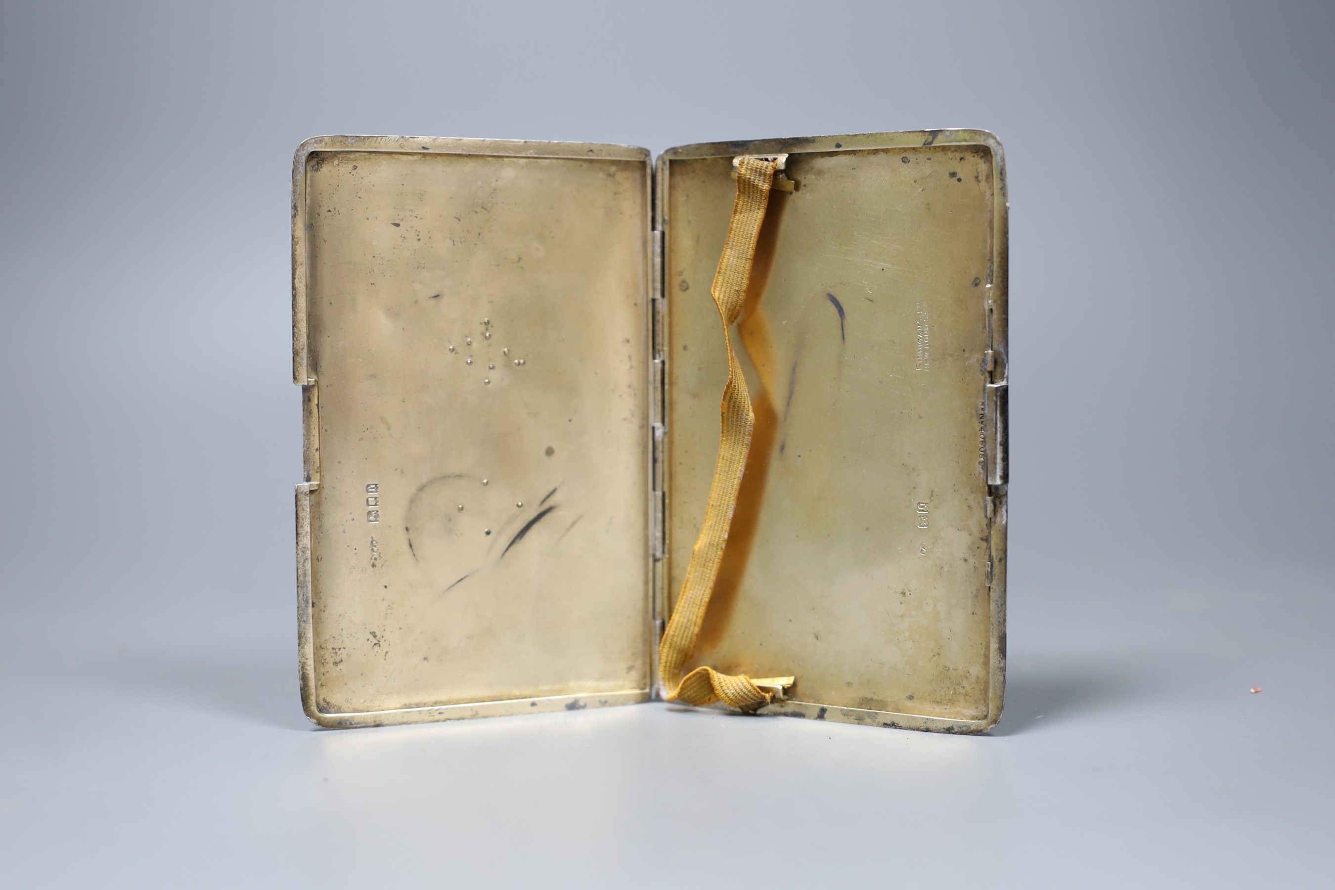 A Finnigans silver engine turned cigarette case with gilt interior mounted with gold Manchester Regiment 'Egypt' badge and family crest, London 1917, width 13cm